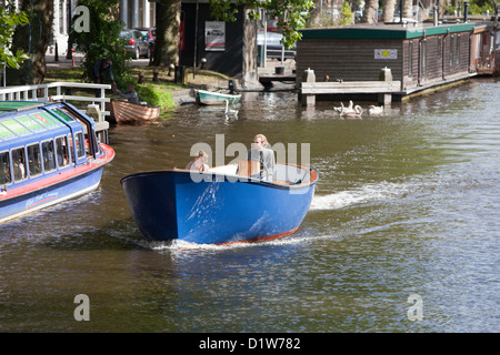 Barca che scivola giù il fiume di Amsterdam in un giorno caldo e soleggiato Foto Stock