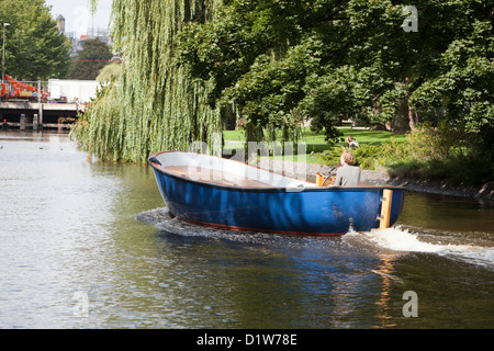 Barca che scivola giù il fiume di Amsterdam in un giorno caldo e soleggiato Foto Stock