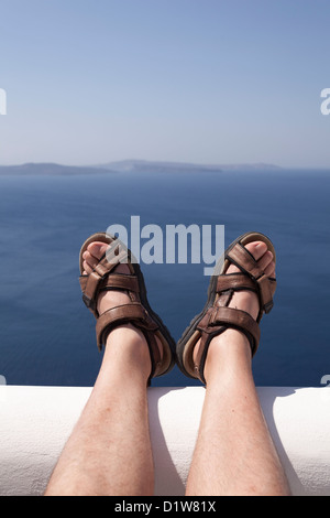 Uomo di gambe e piedi sulla parete con vista mare, Grecia Foto Stock