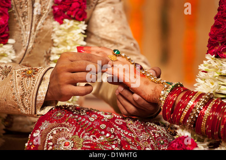 Close-up di un groom mettendo un anello di nozze su una sposa Foto Stock