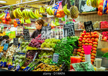 Una donna vende produrre nel suo negozio al Mercato di Boqueria a Barcellona, Spagna. Foto Stock