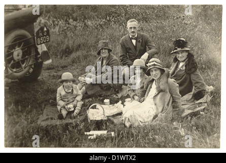 Foto cartolina del gruppo di famiglia degli anni '20 con i loro abiti 'Sunday Best' che hanno un picnic in campagna, Regno Unito Foto Stock