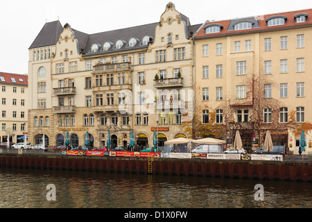 Riverside eleganti edifici con ristoranti e bar su Schiffbauerdamm attraverso il fiume Sprea a Berlino, Germania Foto Stock