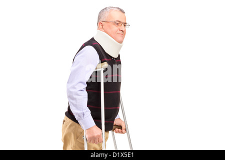 Un gentiluomo con supporto a collo usando stampelle isolati su sfondo bianco Foto Stock