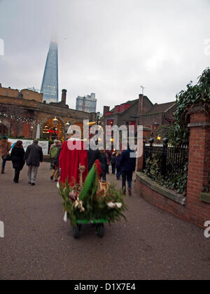 La folla essendo ha portato alla storica George Inn di Borough High Street come parte delle celebrazioni durante la Twelfth Night Festival il 6 gennaio, 2012 che mostra la Shard London Bridge in background, Bankside Riverwalk, Londra, Inghilterra, Regno Unito. La dodicesima notte è un libero stagionale annuale celebrazione svoltasi nella Bankside area di Londra. Si tratta di una celebrazione del nuovo anno, la miscelazione di antiche tradizioni stagionali con festa contemporanea. Foto Stock