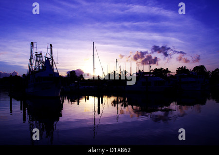 La pesca a strascico e barche a vela stagliano contro un cielo blu all'alba con acqua riflessioni. Foto Stock