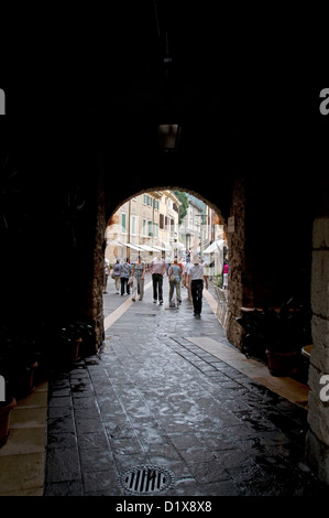 Sotto un arco medievale pedonale in Via Spagna, una strada popolare per i turisti nella piccola cittadina di Garda sul Lago di Garda in Veneto Foto Stock