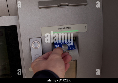 L'uomo inserendo bankcard in ATM Foto Stock