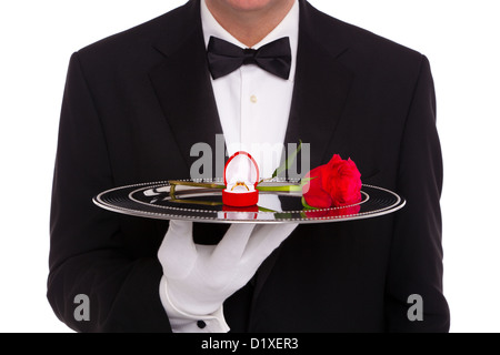 Un maggiordomo tenendo un vassoio d'argento su cui è un diamante anello di fidanzamento in un cuore a forma di scatola di gioielli e una singola rosa rossa Foto Stock
