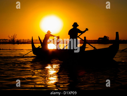 Battellieri birmano canottaggio sul Lago Taungthaman al tramonto, Amarapura vicino a Mandalay in Birmania (Myanmar), Sud-est asiatico. Foto Stock