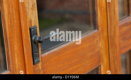 Close up di un ferro battuto maniglia su una porta vetrata su una nuova stalla di conversione. Foto Stock