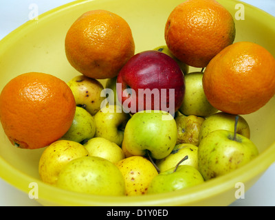 Giallo recipiente di materia plastica con mele e mandarini Foto Stock