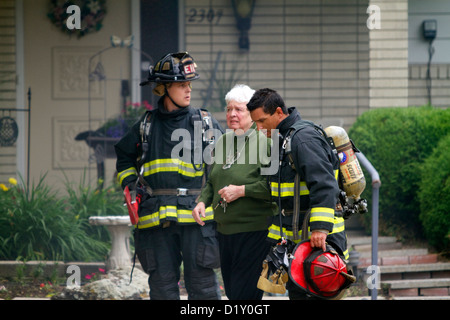 I vigili del fuoco di assistere un residente durante un incendio a Boise, Idaho, Stati Uniti d'America. Foto Stock