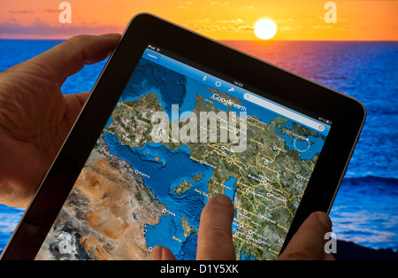 Apple iPad smart tablet con applicazione Google Earth sullo schermo che presenta Europa continentale orientale, Francia Africa ecc, mare e tramonto in background Foto Stock