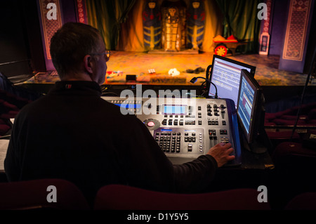 Un uomo alla guida di una illuminazione digitale controllo scheda desk presso un professionista theatre venue REGNO UNITO Foto Stock