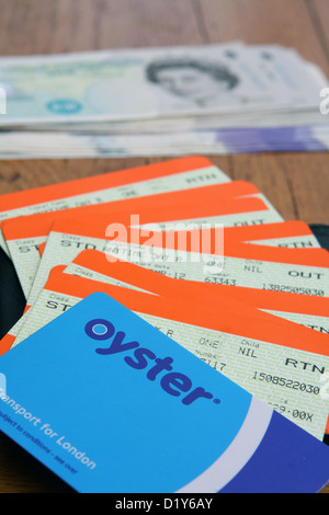 Un Oyster card e biglietti ferroviari su un portafoglio nero con sterling note in background Foto Stock