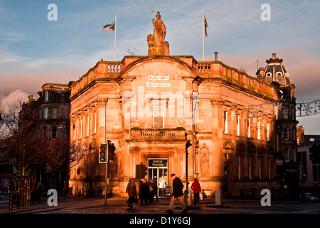 Basso livello di inverno che riflette la luce solare e la colata lunghe ombre scure in ottica Express edificio retail a Dundee, Regno Unito Foto Stock