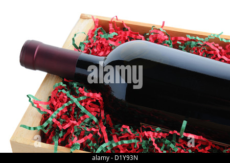 Primo piano di un vino rosso bottiglia in un legno nella cassa di spedizione con shredded carta di riempimento in vacanza di Natale a colori. Foto Stock