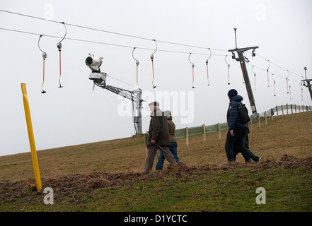 I turisti a piedi sotto un impianto di risalita passato un cannone da neve su un arida di sci a Willingen, Germania, 08 gennaio 2013. Basse temperature abbastanza anche per essere in grado di utilizzare cannoni da neve non sono previste prima del prossimo weekend. Foto: UWE ZUCCHI Foto Stock