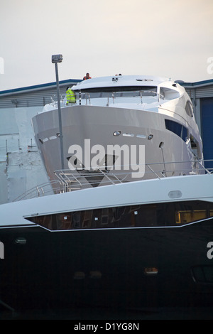 Uomini al lavoro sul lusso Sunseeker barche a Poole Quay nel dicembre Foto Stock