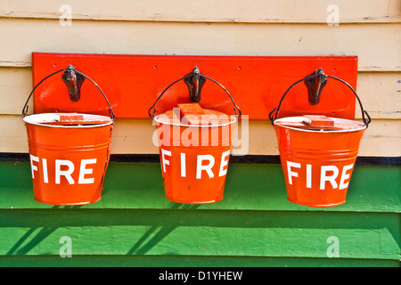 Tre red fire bucket appeso a una parete a Pickering stazione ferroviaria Nord Yorkshire Inghilterra Europa Foto Stock