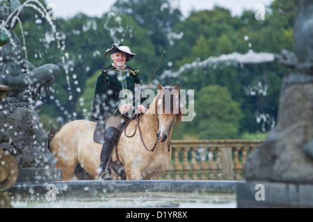 Frederiksborger con pilota in costume storico in piedi dietro una fontana nel giardino di Palazzo Frederiksborg Foto Stock