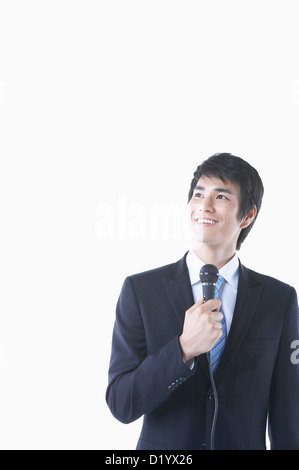 Un imprenditore in un vestito nero tenendo un microfono cercando Foto Stock