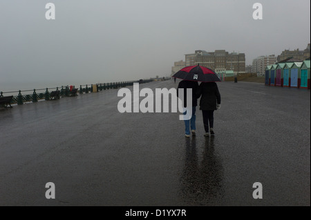 Giovane a piedi nella pioggia sotto ombrellone, Brighton e Hove Foto Stock
