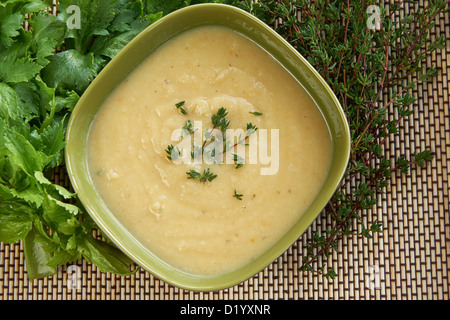 Crema calda di sedano rapa zuppa in una ciotola verde sul tavolo con timo fresco e il sedano. Migliori per l'autunno freddo e il cattivo tempo. Foto Stock