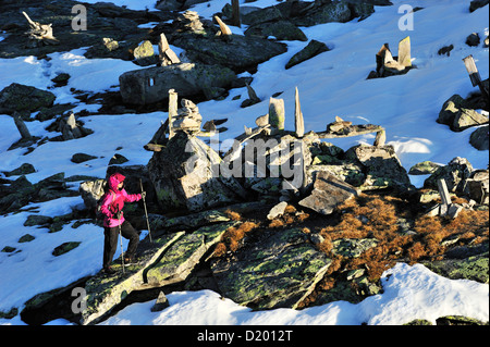 Donna che cammina attraverso la coperta di neve rocce e cairns, Peterskoepfl, gamma Zillertal, Zillertal, Tirolo, Austria Foto Stock