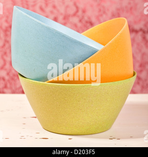 Tre tazze colorate alla rinfusa impilati su un vecchio tavolo da cucina. Foto Stock