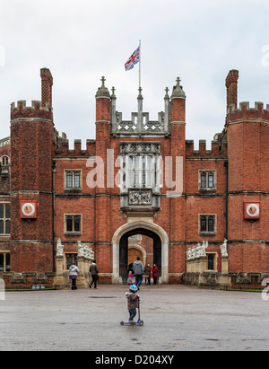 Piccolo bambino su scooter di fronte all'entrata principale del Palazzo di Hampton Court Foto Stock