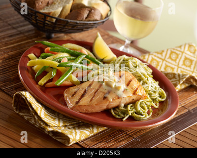 Cena di salmone con aglio arrostito su pesto pasta e servita con verdure medley Foto Stock