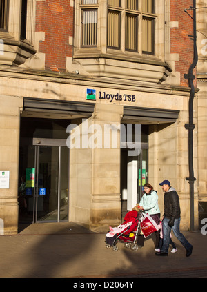 Una giovane coppia con un bambino a piedi passato Lloyds TSB Bank in Church Street nr High Street Sheffield Inghilterra Foto Stock