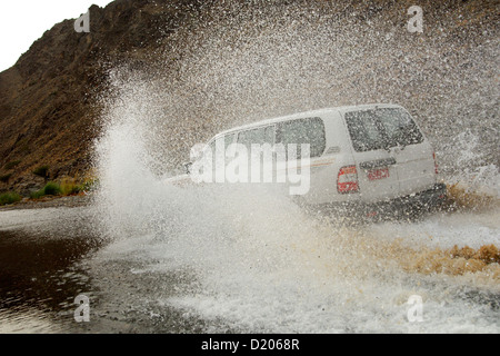 Wadi Bashing, Toyota veicolo fuoristrada sbatti attraverso pozzanghere in Wadi Al Abyad, Al Batinah regione, il sultanato di Oman Foto Stock