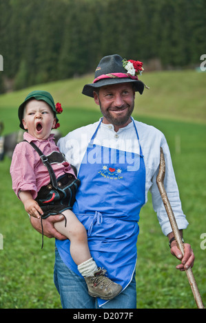 L'agricoltore e figlio di indossare abiti tradizionali, guidare dal recinto pascoli di montagna, Almabtrieb, Val d'Ultimo, Alto Adige, Italia Foto Stock