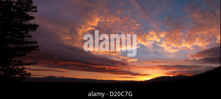 Rosso e oro nuvole di compensazione contro il cielo blu sulle colline di sunrise Foto Stock