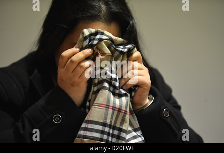 Il 19-anno-vecchio convenuta Sehrivan A. si nasconde dietro una sciarpa come egli attende l'inizio del suo processo presso il tribunale regionale di Oldenburg, Germania, 09 gennaio 2013. Egli è accusato di tentato omicidio dopo aver accoltellato la sua gravidanza ragazza nello stomaco in estate 2012. Foto: CARMEN JASPERSEN Foto Stock