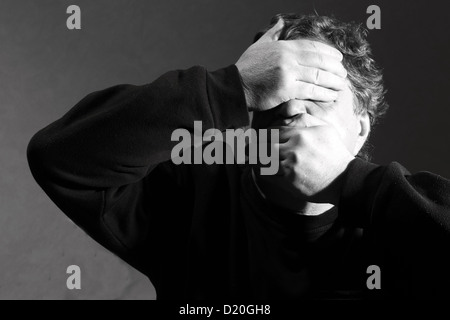 L'uomo chiuso gli occhi e la bocca con le mani Foto Stock