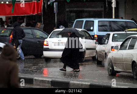 Gen. 10, 2013 - Gaza City, nella Striscia di Gaza, Territori palestinesi - i palestinesi a piedi in una strada come meteo invernale spazzato attraverso la regione di Gaza City il 10 gennaio 2013. Tempeste anormale, che per quattro giorni hanno fatto brillare il Medio Oriente con la pioggia, neve e grandine, lasciare fasce di Israele e della Giordania sotto una coltre di neve e parti del Libano oscurati (credito Immagine: © Majdi Fathi/immagini APA/ZUMAPRESS.com) Foto Stock