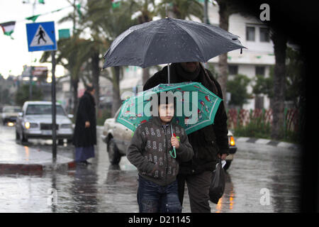 Gen. 10, 2013 - Gaza City, nella Striscia di Gaza, Territori palestinesi - i palestinesi a piedi in una strada come meteo invernale spazzato attraverso la regione di Gaza City il 10 gennaio 2013. Tempeste anormale, che per quattro giorni hanno fatto brillare il Medio Oriente con la pioggia, neve e grandine, lasciare fasce di Israele e della Giordania sotto una coltre di neve e parti del Libano oscurati (credito Immagine: © Majdi Fathi/immagini APA/ZUMAPRESS.com) Foto Stock