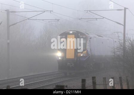 Renfrewshire, Scozia, Regno Unito, giovedì 10 gennaio 2013. Un treno elettrico Scotrail che viaggia in nebbia sulla Glasgow per Ayr linea vicino Lochwinnoch. Foto Stock