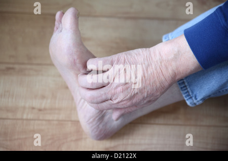 Una mano d'uomo sulla sua itchy piede Foto Stock