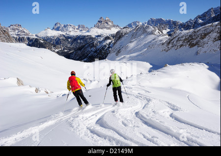 Giovane donna e giovane uomo in discesa con gli sci crosscountry dal Corno d'angolo, Tre Cime di Lavaredo in background, Corno d'Ang Foto Stock