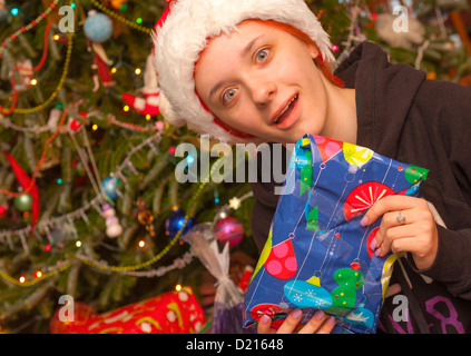 Un adolescente di sesso femminile si apre un regalo il giorno di Natale. Foto Stock