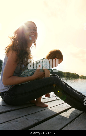 Donna con bambino piccolo, seduto sul molo in legno, Vecchio Danubio, Vienna, Austria Foto Stock