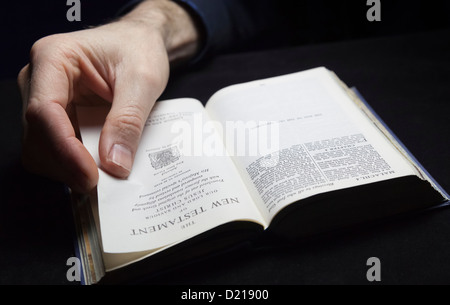 Un uomo la lettura della Sacra Bibbia con una sola mano. Foto Stock