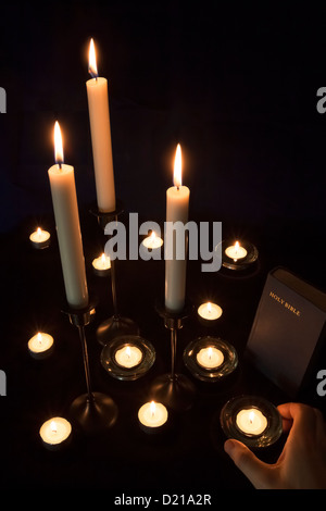Una mano mettendo candele sull'alter Foto Stock