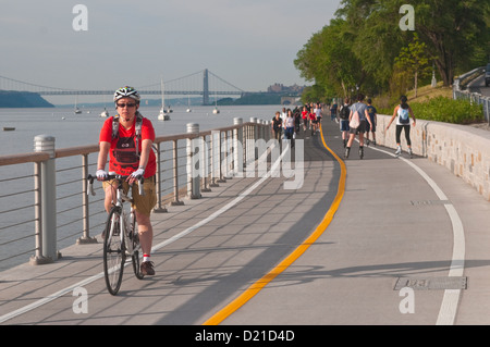 La donna in sella ad una bicicletta sul lungofiume in Riverside Park Foto Stock