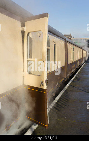 La sala con il treno alla stazione di seppellire sulla East Lancashire Railway. Il vapore è il riscaldamento delle carrozze prima ai passeggeri di salire a bordo. Foto Stock